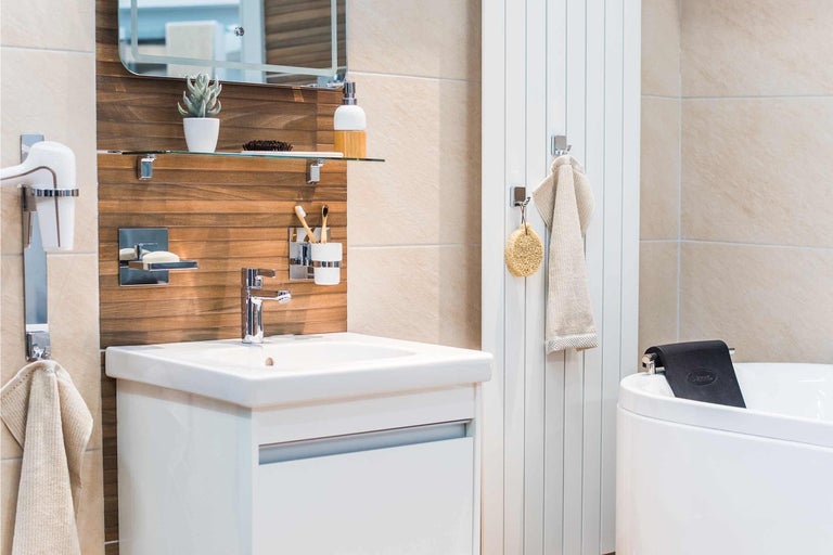 Světlá koupelna s umyvadlem, zrcadlem, úložným prostorem a vanou pro přátelskou atmosféru.