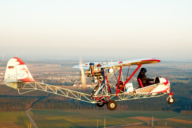 Ultralehké letadlo s pilotem za letu nad krajinou