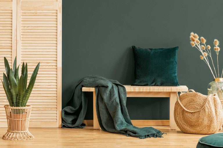 Obývací pokoj s dřevěnou lavicí, polštářem, dekou, rostlinou a dekorativními předměty