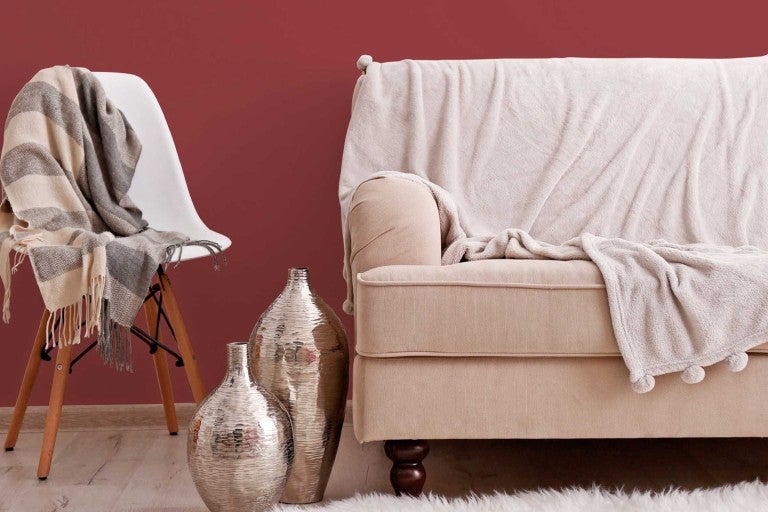 Obývací pokoj s pohovkou, židlí, přikrývkami a ozdobnými vázami.