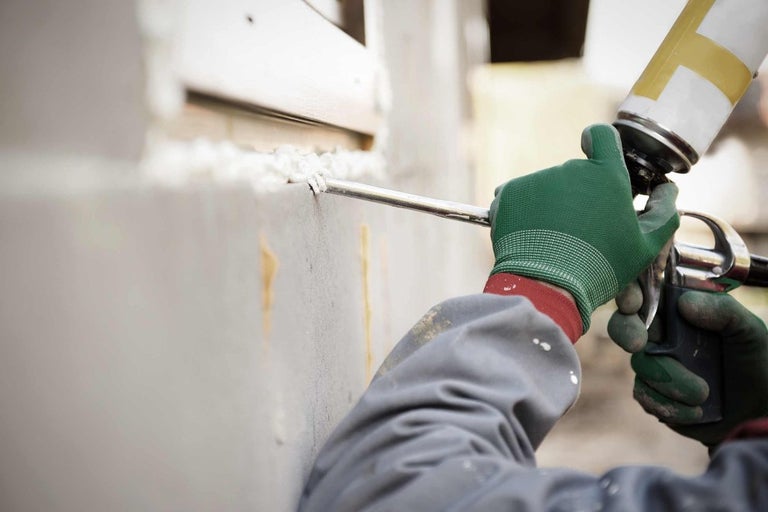 Pracovník používá stavební pěnu k utěsnění okna.