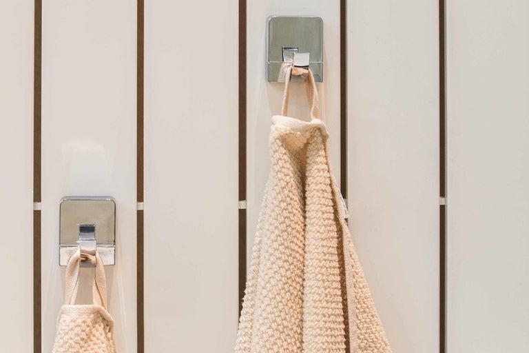 Ručníky visí na kovových koupelnových háčcích na zdi