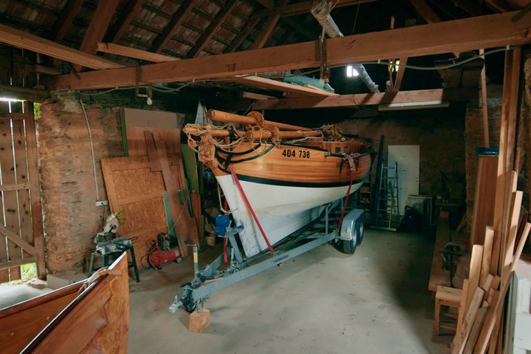 Dřevěná loď na přívěsu v garáži.