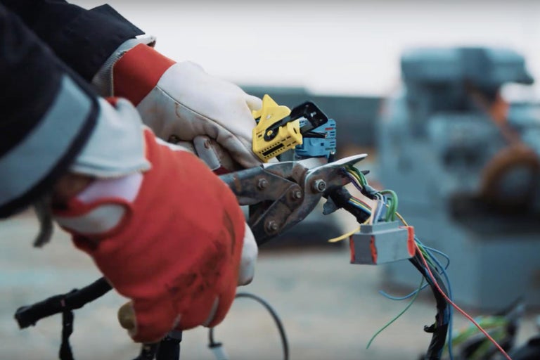 Osoba v rukavicích používá kleště k práci na kabelovém svazku