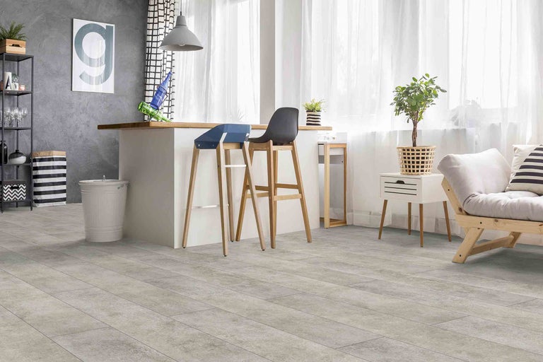 Světlý obývací pokoj s barovými stoličkami, dekorací a světlou vinylovou podlahou se vzhledem dřeva.