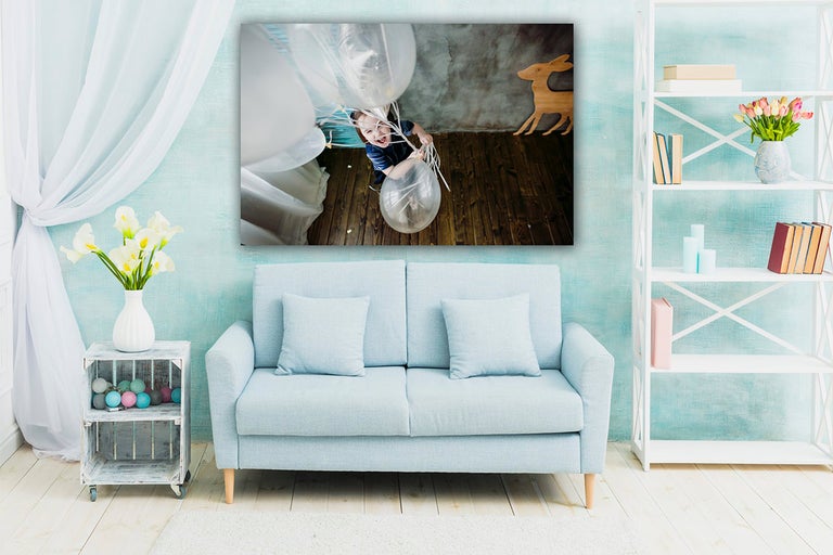 Obývací pokoj s pohovkou a zavěšeným plátnem obrazu chlapce s balónky