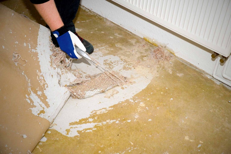 Osoba odstraňuje kobercovou krytinu řezacím nožem.