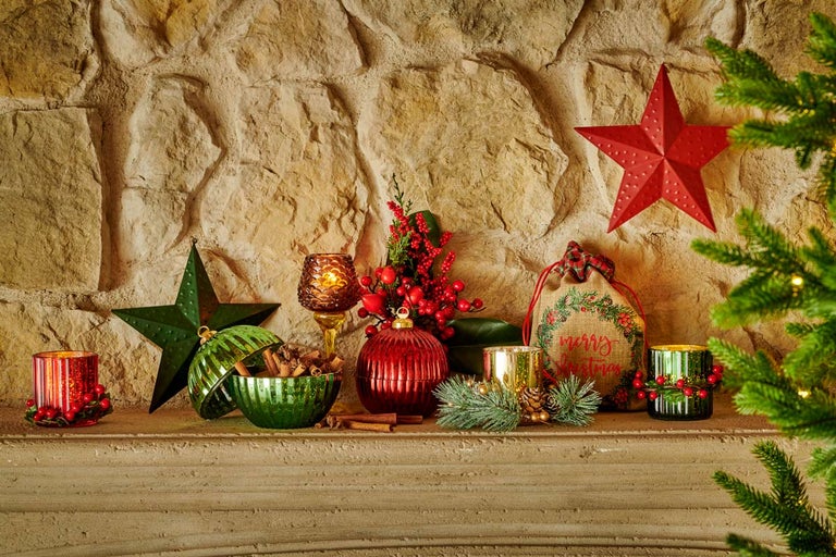 Ozdobný krb s vánočními dekoracemi, včetně svícnů, hvězd a dárkové tašky