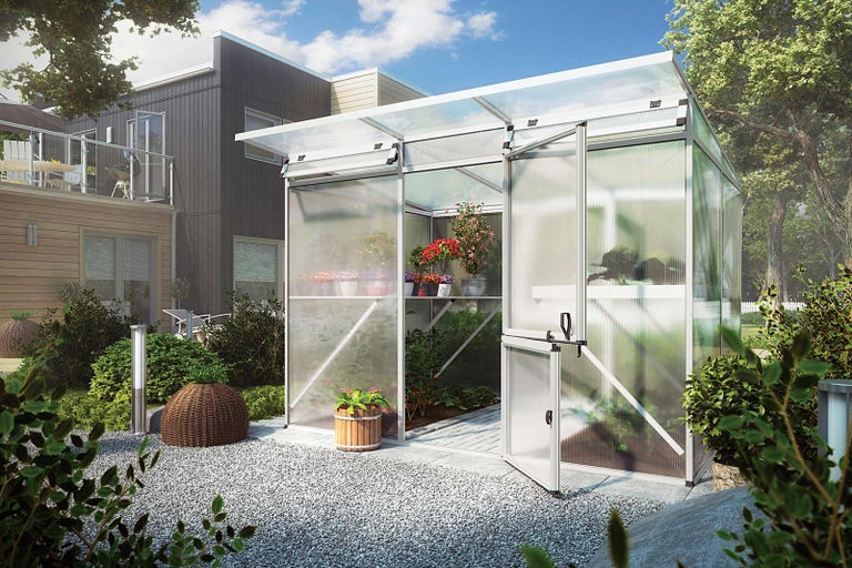 Skleník s otevřenými dveřmi a rostlinami na zahradě