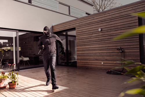 Zloděj se šroubovákem na dřevěné terase před domem.