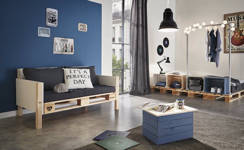 Obývací pokoj s nábytkem z palet, včetně paletové pohovky, stolu a úložného řešení