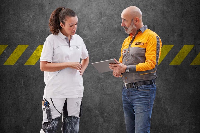 Dva řemeslníci v pracovním oděvu, jeden drží tablet.