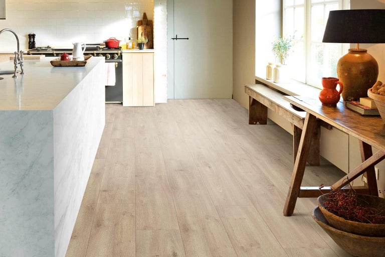 Světlá laminátová podlaha v kuchyni a obývacím pokoji.