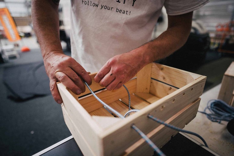 Osoba navléká provaz dřevěnou bednou