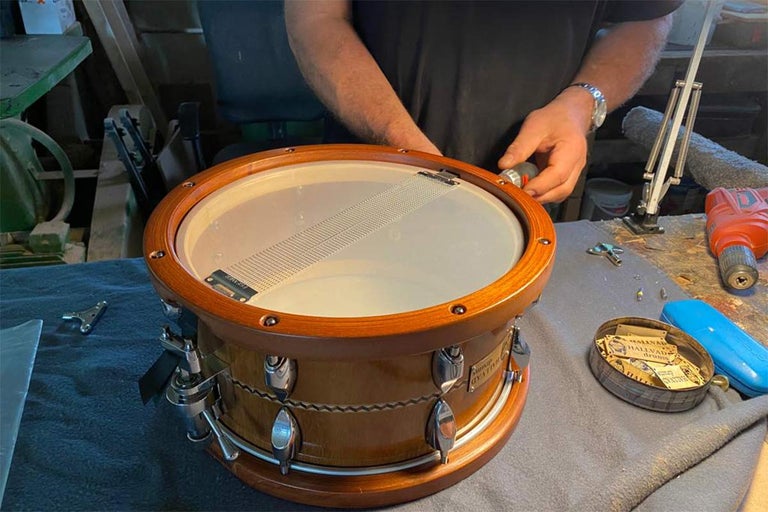 Řemeslník montuje dřevěný buben pomocí nástrojů na pracovním stole