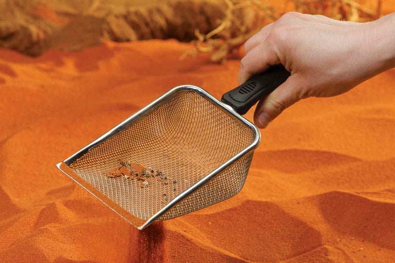 Ruční síto s rukojetí držené v písku