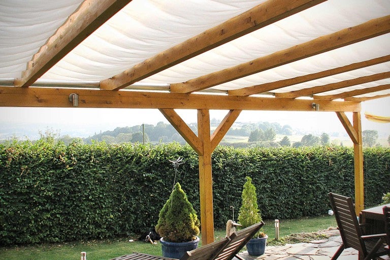 Dřevěná pergola se sluneční ochranou a zahradním nábytkem na zahradě