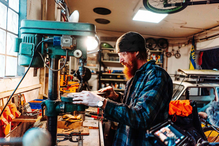 Muž pracuje se sloupovou vrtačkou v dílně.