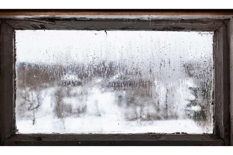 Okno s kondenzací a výhledem na zasněženou krajinu