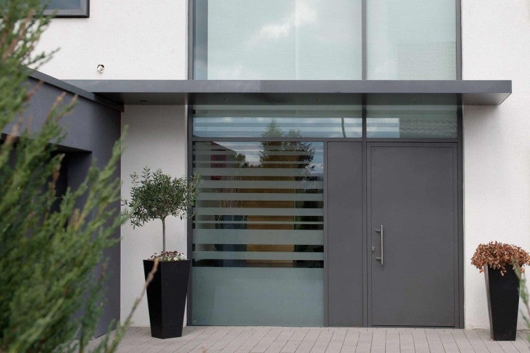 Vstupní prostor domu s vchodovými dveřmi, boční díl s ochrannou fólií a květináči.