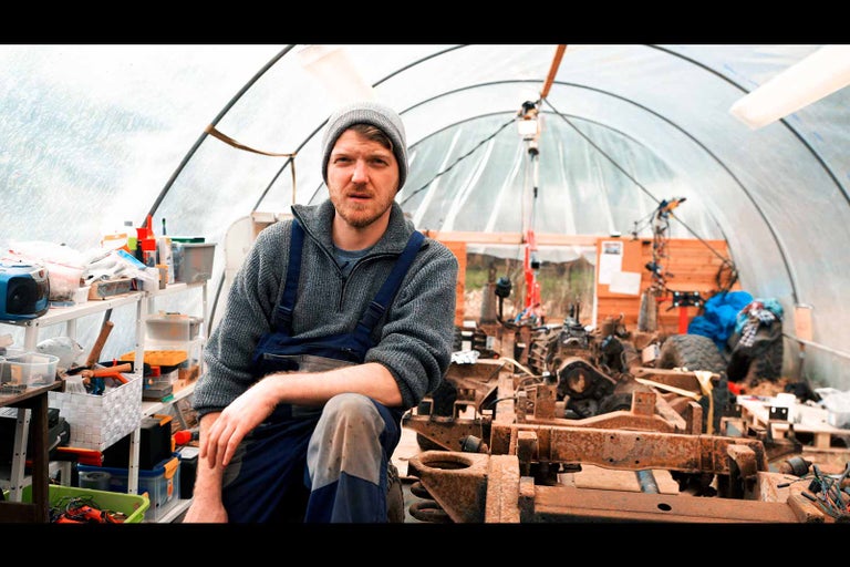 Muž sedí v dílně s rámem vozidla