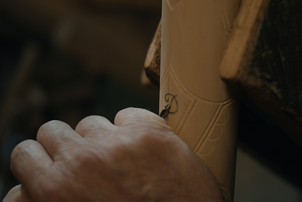 Řemeslník vyřezává vzor do dřevěného předmětu