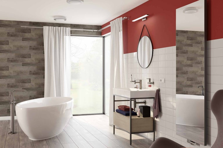 Koupelna s volně stojící vanou, umyvadlem se skříňkou, zrcadlem a obkladem stěn s dřevěným vzhledem