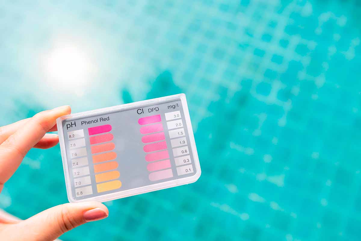 Ruka drží tester bazénu pro měření hodnoty pH a obsahu chloru