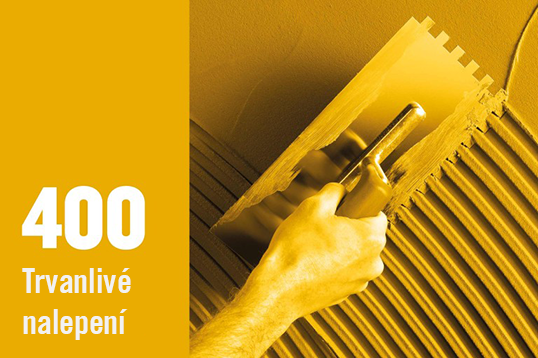 Nanášení lepidla na obklady pomocí zubové stěrky pro trvanlivé lepení.