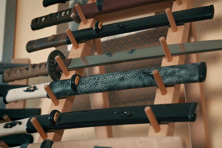 Několik katan je vystaveno na dřevěném stojanu.