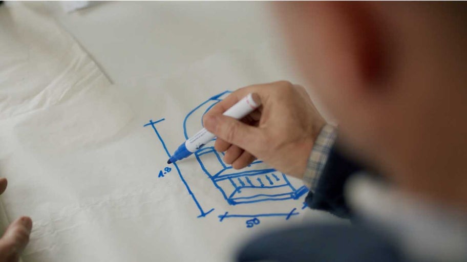 Osoba kreslí skicu nábytku fixem na papír.