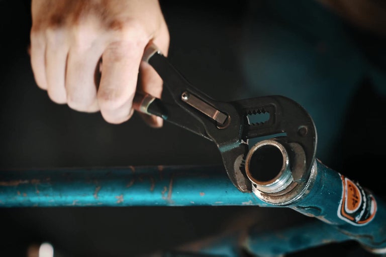 Instalatér s kleštěmi na trubky na trubce.