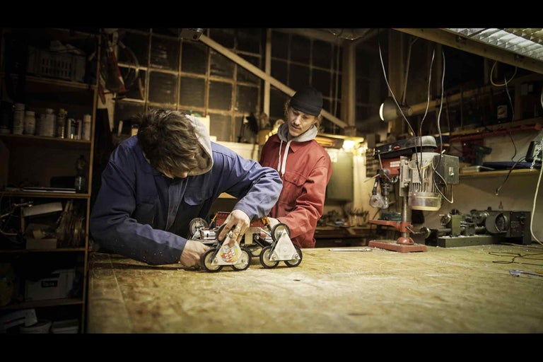 Dílna se dvěma lidmi pracujícími na robotickém vozidle
