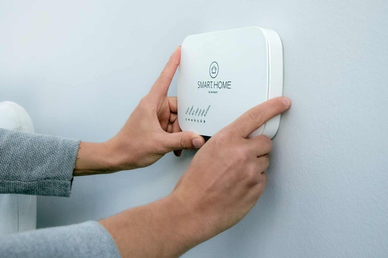 Osoba montuje centrálu Smart Home na zeď