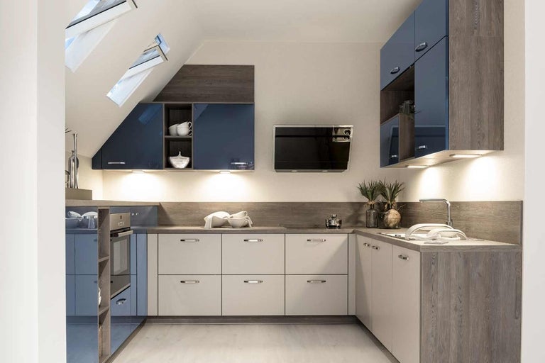 Kuchyně s horními a spodními skříňkami a vestavěnými spotřebiči pod střešními okny