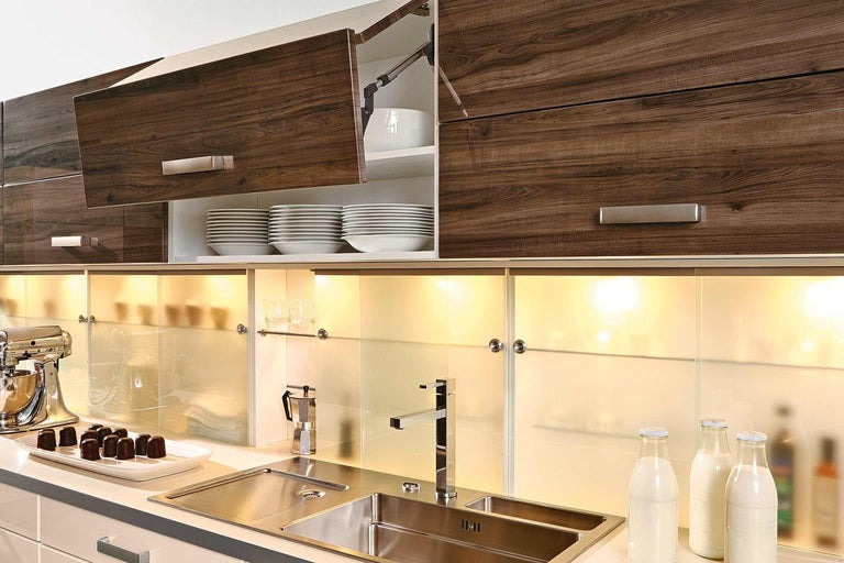 Kuchyňská scéna s dřezem, vodovodní baterií, kuchyňským robotem a závěsnými skříňkami s dřevěnou strukturou