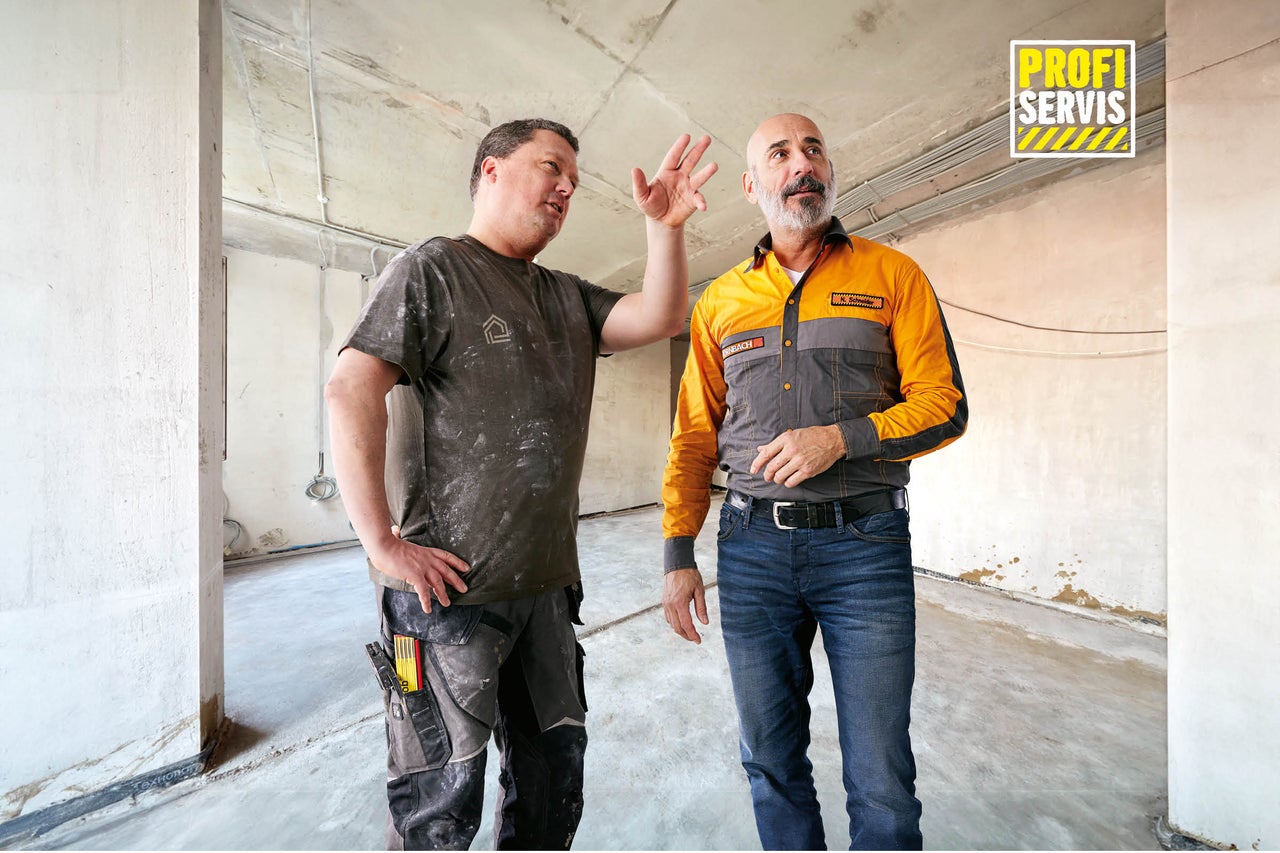 Dva řemeslníci diskutují o stavebním projektu v hrubé místnosti