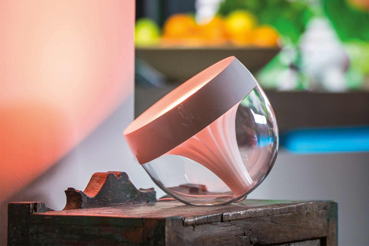 Stolní lampa Philips Hue Iris ze skla na dřevěném stole