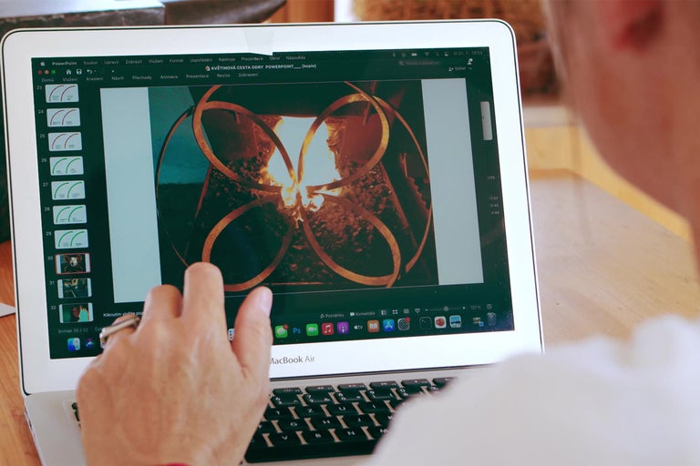 Osoba pracuje na MacBooku Air s prezentací o květinové cestě.