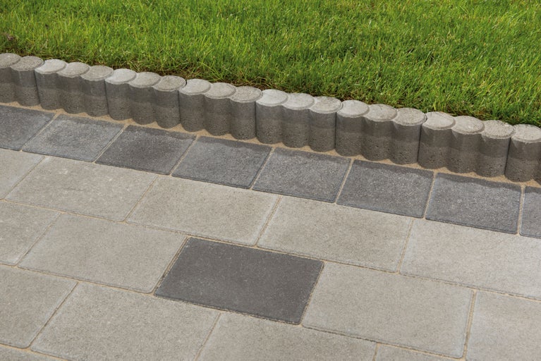 Dlážděné kameny a obrubníky na trávníku.