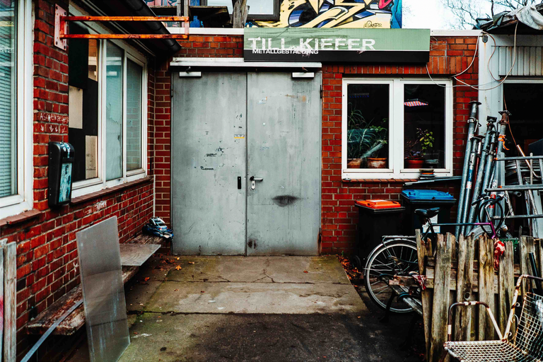 Vnější pohled na kovovýrobní závod s cihlovou zdí, dvoukřídlými dveřmi a okny.