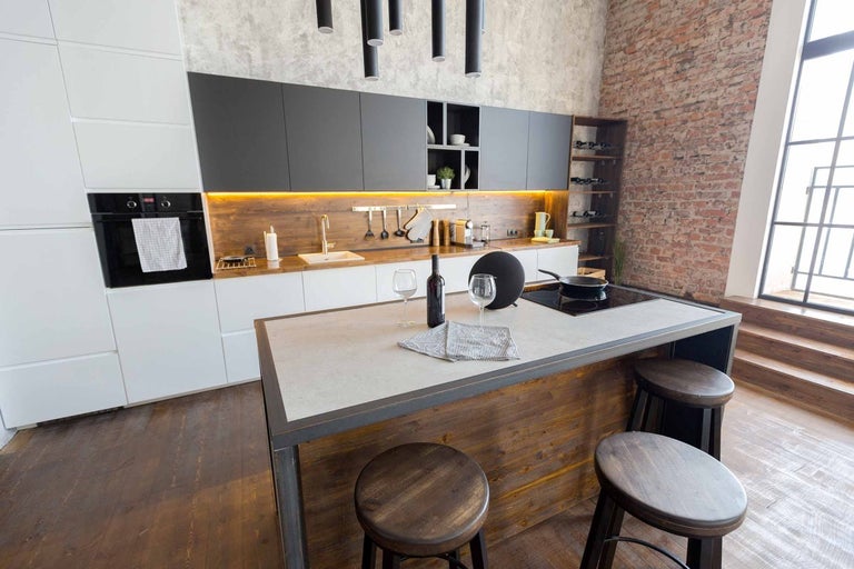 Moderní kuchyně s kuchyňským ostrovem, barovými stoličkami a cihlovou zdí