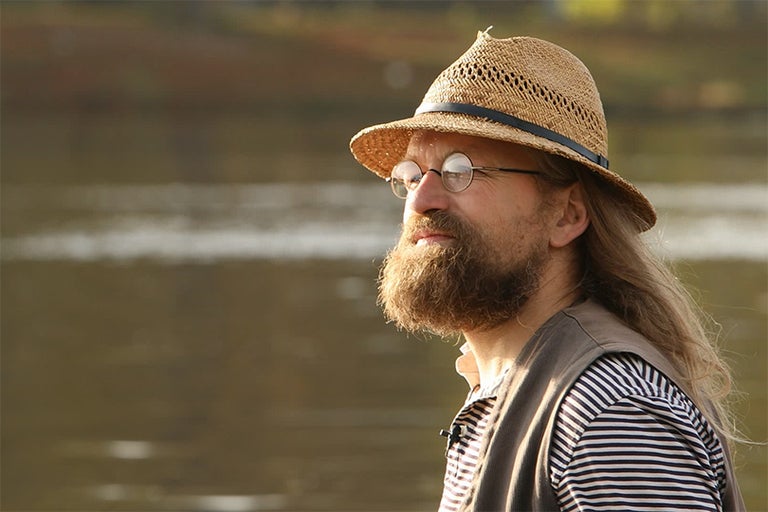 Portrét muže s vousy, kloboukem a brýlemi venku