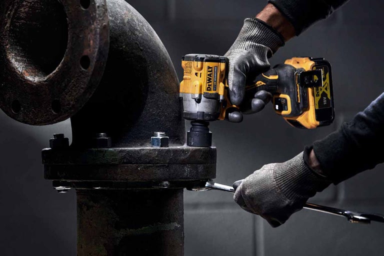 Akumulátorový rázový utahovák DeWalt se používá na potrubí.