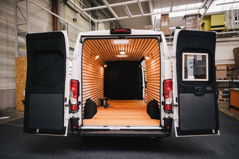 Interiér dodávky s dřevěným obložením a otevřenými zadními dveřmi