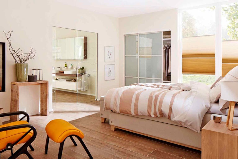 Světlá, přátelská ložnice s postelí, posuvnými dveřmi do koupelny a šatny