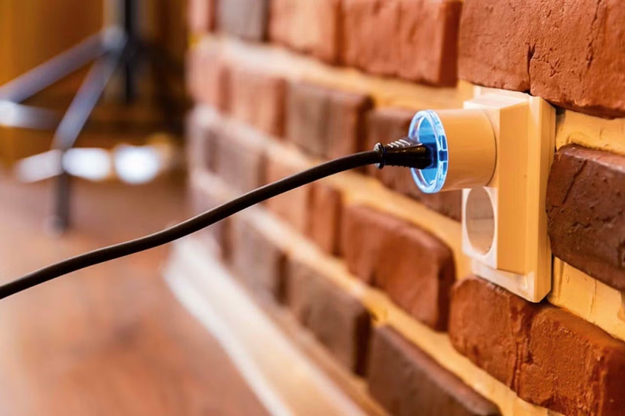 Zásuvka se zástrčkou v cihlové zdi