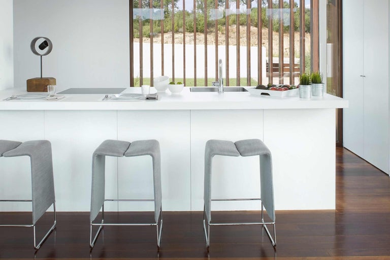 Moderní kuchyně se dvěma barovými stoličkami a bílým kuchyňským ostrovem.