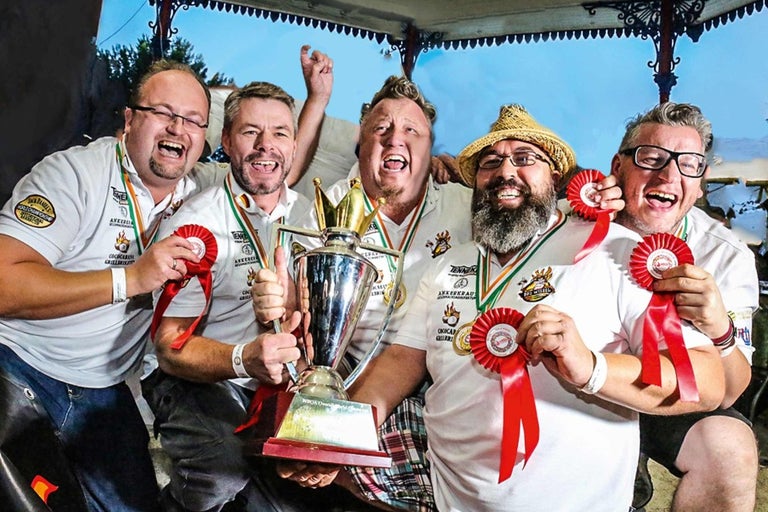 Skupina lidí slaví s pohárem a oceněními