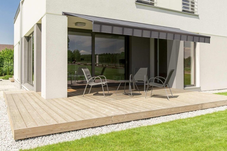 Terasa s markýzou, židlemi a stolem před domem